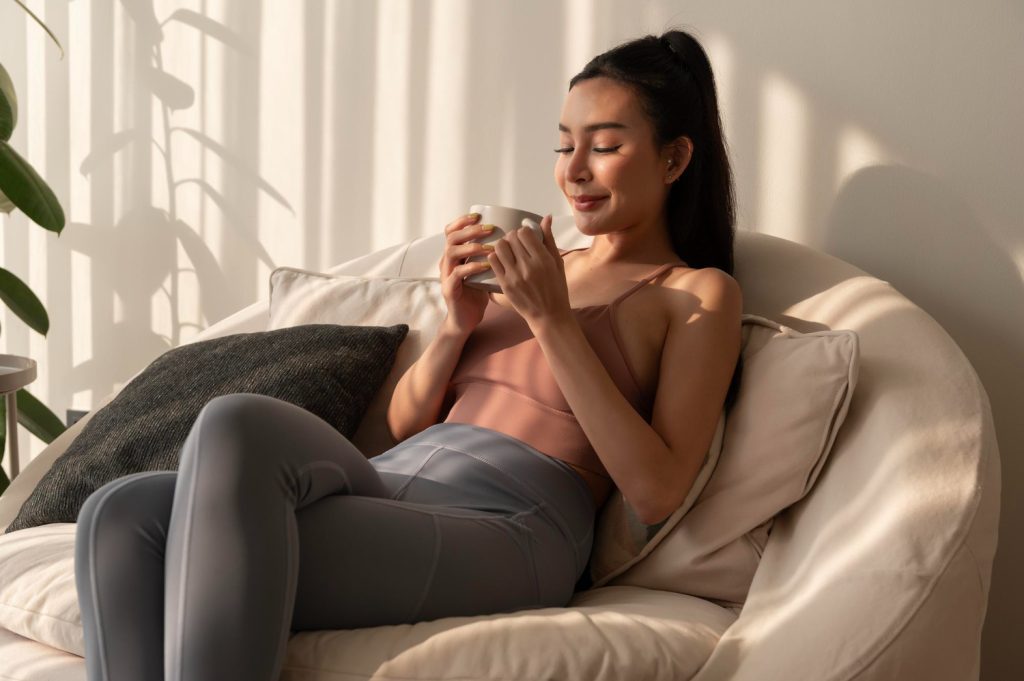 Young asian woman enjoying having coffee in living room at home